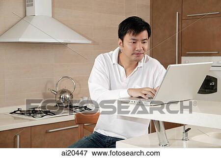 Man in kitchen, using laptop View Large Photo Image Stock Photo - Man in kitchen, using laptop. Fotosearch