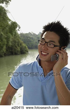 Stock Photography - Man in polo shirt and glasses, using mobile phone. Fotosearch