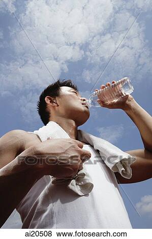 Man in sleeveless T shirt drinking water from bottle View Large Photo Image Stock Photo - Man in sleeveless T shirt drinking water from bottle. Fotosearch
