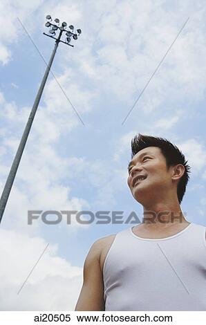 Man in sleeveless T shirt, looking away, low angle view View Large Photo Image Stock Photography - Man in sleeveless T shirt, looking away, low angle view. Fotosearch
