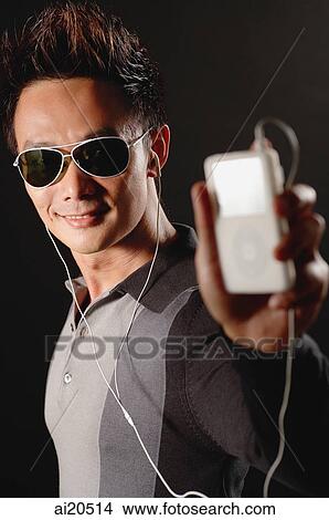 Picture - Man in sunglasses, holding MP3 player. Fotosearch