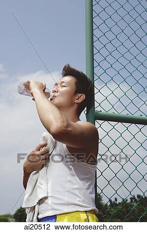 Man leaning on fence, drinking from mineral water bottle View Large Photo Image Stock Image - Man leaning on fence, drinking from mineral water bottle. Fotosearch
