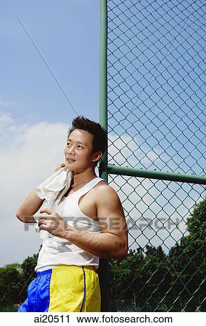 Man leaning on fence, wiping his neck with towel View Large Photo Image Stock Image - Man leaning on fence, wiping his neck with towel. Fotosearch