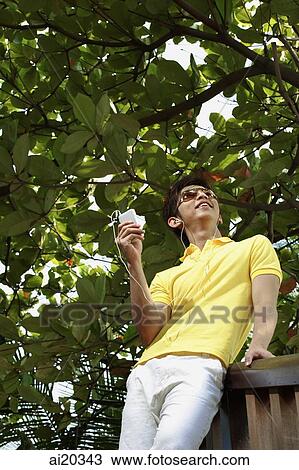 Man listening to Mp3 player, low angle view View Large Photo Image Stock Image - Man listening to Mp3 player, low angle view. Fotosearch