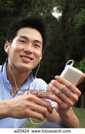 Man listening to MP3 player, portrait View Large Photo Image Picture - Man listening to MP3 player, portrait. Fotosearch