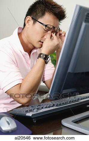 Man sitting in front of computer, hand on nose View Large Photo Image Stock Photograph - Man sitting in front of computer, hand on nose. Fotosearch
