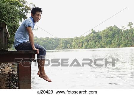 Man sitting on jetty, looking away, smiling View Large Photo Image Stock Photo - Man sitting on jetty, looking away, smiling. Fotosearch