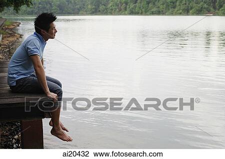 Man sitting on jetty, looking out at water View Large Photo Image Stock Image - Man sitting on jetty, looking out at water. Fotosearch