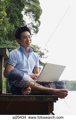 Man sitting on jetty with laptop View Large Photo Image Picture - Man sitting on jetty with laptop. Fotosearch