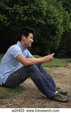 Man sitting on river bank, listening to MP3 player View Large Photo Image Stock Image - Man sitting on river bank, listening to MP3 player. Fotosearch