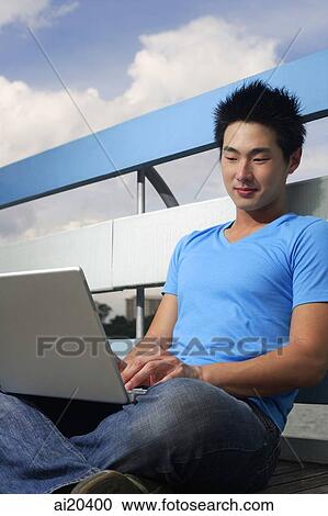 Man sitting outdoors, using laptop View Large Photo Image Stock Image - Man sitting outdoors, using laptop. Fotosearch