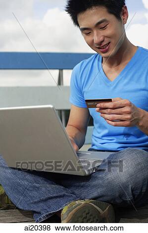 Man sitting with laptop, holding credit card View Large Photo Image Stock Photo - Man sitting with laptop, holding credit card. Fotosearch