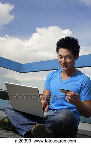 Man sitting with laptop, holding credit card View Large Photo Image Stock Photo - Man sitting with laptop, holding credit card. Fotosearch