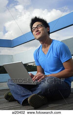 Man sitting with laptop, looking up View Large Photo Image Stock Image - Man sitting with laptop, looking up. Fotosearch