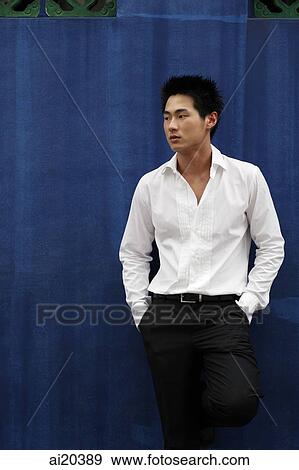 Man standing against blue wall, hands in pockets View Large Photo Image Stock Photo - Man standing against blue wall, hands in pockets. Fotosearch