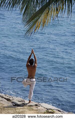 Man standing by the sea, practicing yoga View Large Photo Image Stock Photo - Man standing by the sea, practicing yoga. Fotosearch