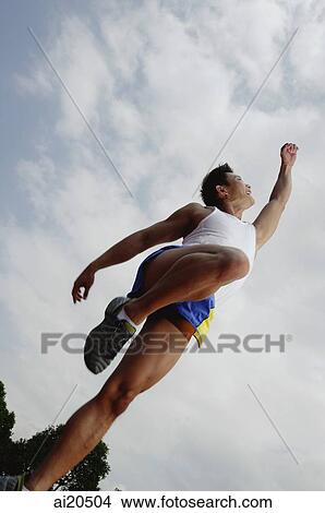 Man standing on one leg, looking up at raised arm View Large Photo Image Picture - Man standing on one leg, looking up at raised arm. Fotosearch