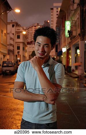 Man standing on street, hand on chin, looking at camera View Large Photo Image Stock Photography - Man standing on street, hand on chin, looking at camera. Fotosearch