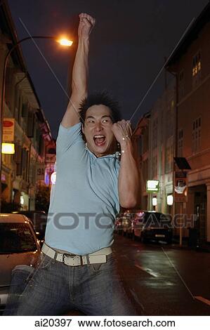 Stock Photo - Man standing on street, raising hand, making a fist. Fotosearch
