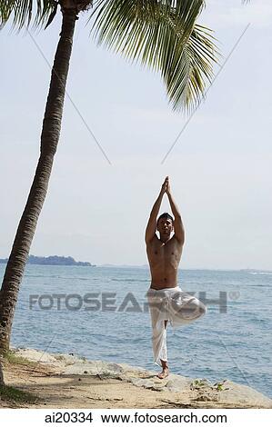 Man standing on the beach, in yoga tree position View Large Photo Image Picture - Man standing on the beach, in yoga tree position. Fotosearch