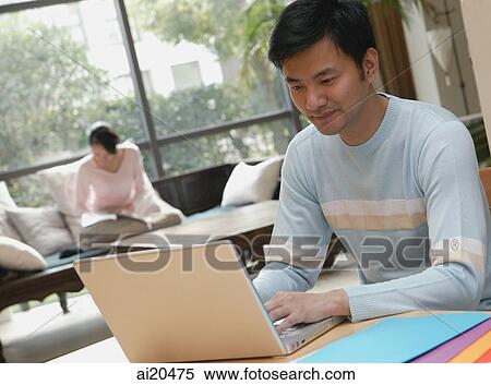 Man using laptop, woman in background reading View Large Photo Image Stock Photography - Man using laptop, woman in background reading. Fotosearch