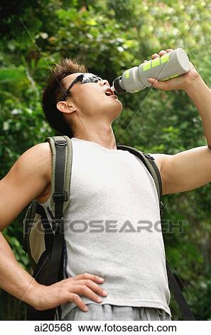 Man with backpack and sunglasses, drinking from water bottle View Large Photo Image Stock Photo - Man with backpack and sunglasses, drinking from water bottle. Fotosearch