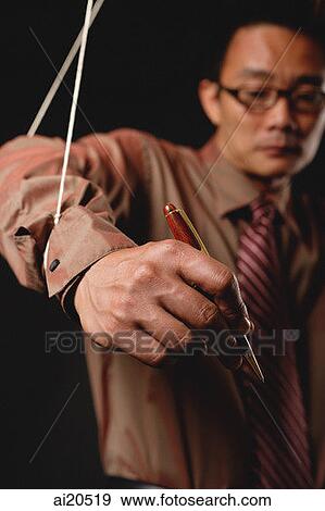 Man with marionette strings attached to his hands, holding pen View Large Photo Image Stock Photo - Man with marionette strings attached to his hands, holding pen. Fotosearch