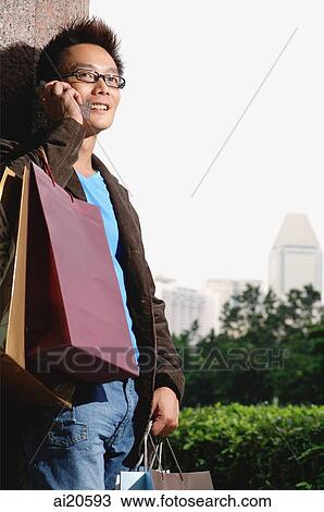 Man with shopping bags, using mobile phone View Large Photo Image Stock Image - Man with shopping bags, using mobile phone. Fotosearch