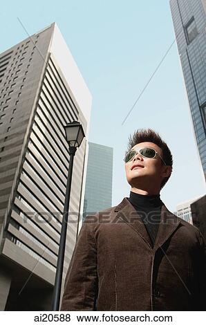 Man with sunglasses, standing, looking away, buildings in the background View Large Photo Image Stock Photo - Man with sunglasses, standing, looking away, buildings in the background. Fotosearch