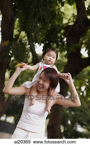Stock Photo - Mother carrying young daughter on shoulder. Fotosearch