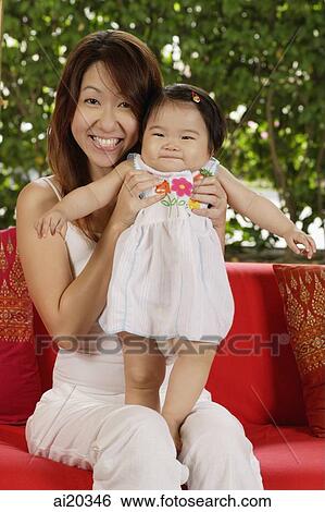 Stock Photograph - Mother holding young daughter, both smiling at camera. Fotosearch