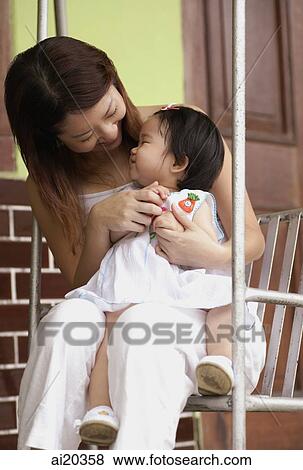 Stock Photo - Mother with young daughter on a swing. Fotosearch