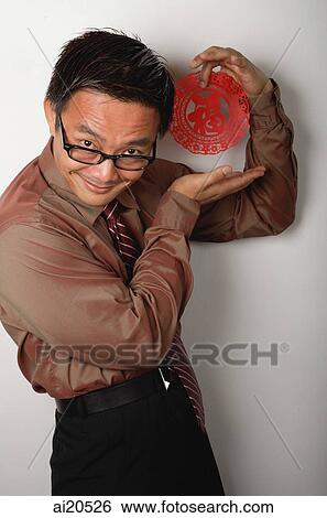 Stock Photograph - Nerdy businessman holding Chinese paper cut out with the word luck. Fotosearch