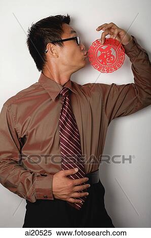 Stock Photography - Nerdy businessman kissing Chinese paper cut out with the word Luck. Fotosearch