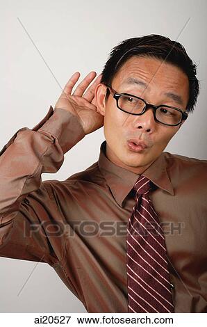 Stock Photo - Nerdy businessman with hand cupped behind ear. Fotosearch
