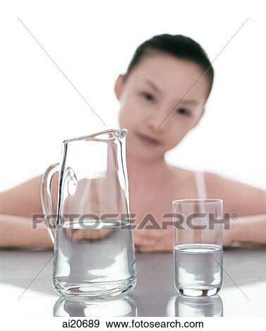 Pitcher and glass of water in foreground, woman in the background View Large Photo Image Stock Photo - Pitcher and glass of water in foreground, woman in the background. Fotosearch