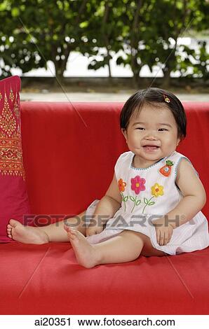 Portrait of baby girl sitting on a red sofa, smiling View Large Photo Image Stock Image - Portrait of baby girl sitting on a red sofa, smiling. Fotosearch