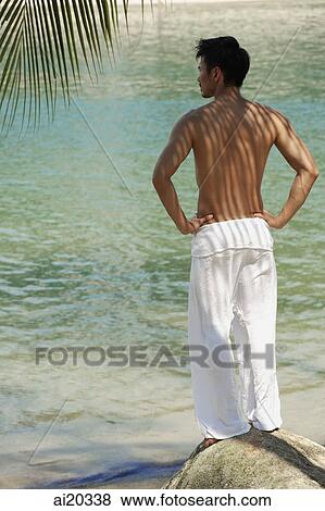 Shirtless man standing on the beach, hands on hip, rear view View Large Photo Image Stock Photo - Shirtless man standing on the beach, hands on hip, rear view. Fotosearch
