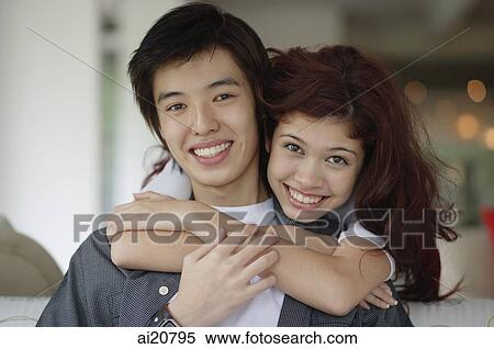 Teenage couple embracing, smiling at camera View Large Photo Image Stock Photography - Teenage couple embracing, smiling at camera. Fotosearch