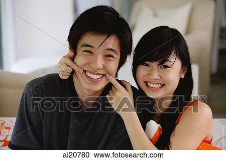 Teenage couple sitting side by side, smiling at camera View Large Photo Image Stock Image - Teenage couple sitting side by side, smiling at camera. Fotosearch