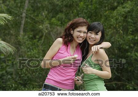 Teenage girls standing side by side, embracing, listening to MP3 player View Large Photo Image Stock Image - Teenage girls standing side by side, embracing, listening to MP3 player. Fotosearch