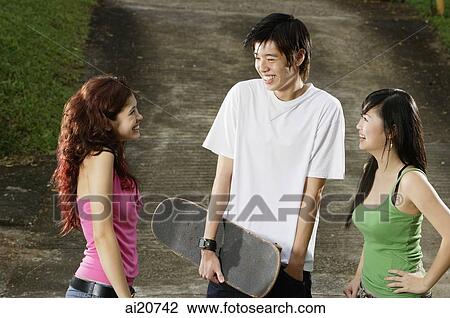 Three teenagers talking, young man holding skateboard View Large Photo Image Stock Image - Three teenagers talking, young man holding skateboard. Fotosearch