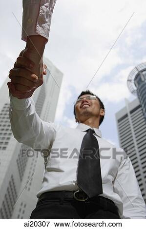 Two businessmen shaking hands, low angle view View Large Photo Image Stock Photo - Two businessmen shaking hands, low angle view. Fotosearch