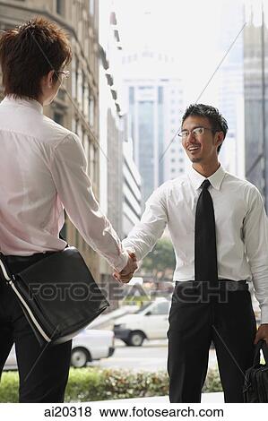 Two businessmen shaking hands, buildings in the background View Large Photo Image Stock Photo - Two businessmen shaking hands, buildings in the background. Fotosearch