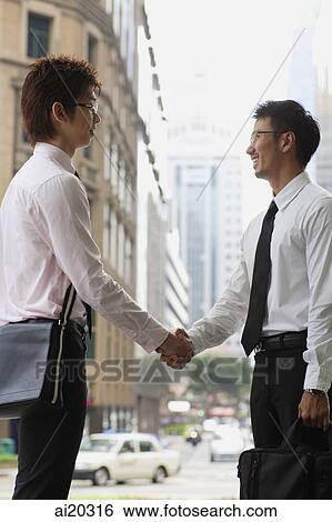 Two businessmen shaking hands, urban location View Large Photo Image Stock Photograph - Two businessmen shaking hands, urban location. Fotosearch