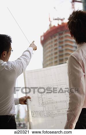 Two men looking at blueprint and buildings in the background View Large Photo Image Stock Image - Two men looking at blueprint and buildings in the background. Fotosearch