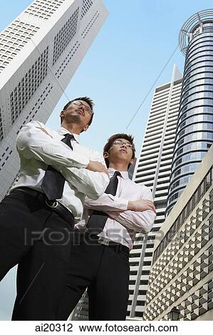 Two men standing with arms crossed, buildings in the background View Large Photo Image Stock Image - Two men standing with arms crossed, buildings in the background. Fotosearch