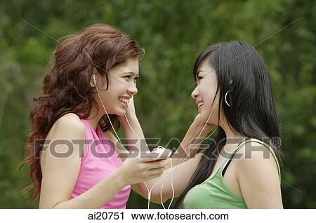 Two teenage girls listening to MP3 player, smiling View Large Photo Image Stock Image - Two teenage girls listening to MP3 player, smiling. Fotosearch