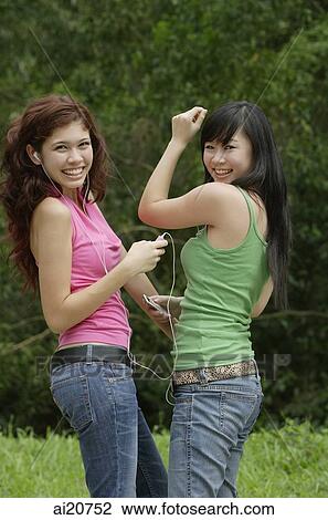 Two teenage girls listening to MP3 player, dancing and smiling at camera View Large Photo Image Stock Image - Two teenage girls listening to MP3 player, dancing and smiling at camera. Fotosearch