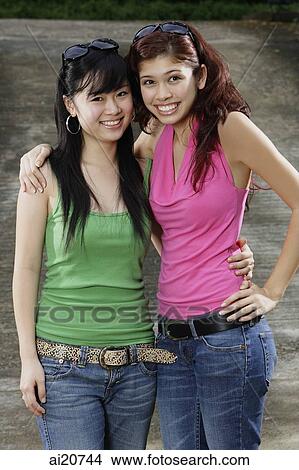 Two teenage girls, standing side by side, smiling at camera View Large Photo Image Picture - Two teenage girls, standing side by side, smiling at camera. Fotosearch